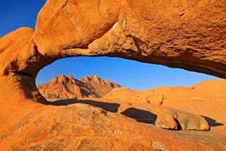 Arco natural en Spitzkoppe con rocas naranjas brillantes bajo un cielo azul | MSC Cruceros