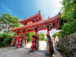 A vibrant traditional gate marking the entrance to Shuri Castle in Naha, Japan, surrounded by lush greenery | MSC Cruises