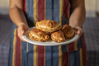 A woman in an apron presents a plate of delicious empanadas | MSC Cruises