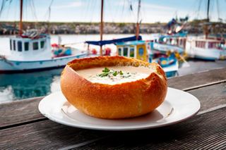 Délicieuse soupe de palourdes servie dans un bol en pain avec des bateaux en arrière-plan | MSC Croisières