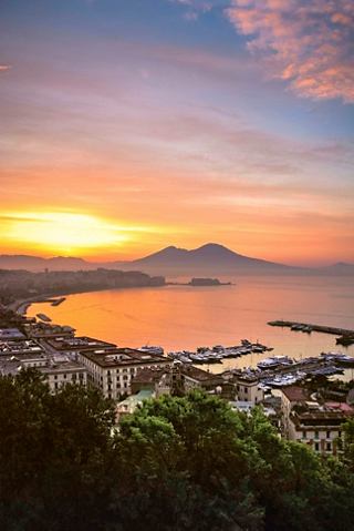 A breathtaking sunset over Naples with Mount Vesuvius in the background, showcasing the beauty of the Mediterranean coastline | MSC Cruises