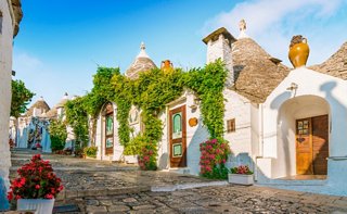 Charming trulli houses with lush greenery lining a picturesque street in Alberobello, Italy | MSC Cruises
