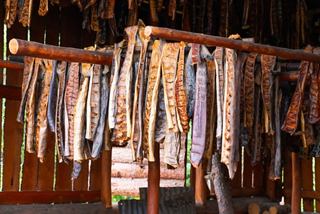 Filetes de salmón colgados secándose en un ahumadero, destacando las ricas tradiciones culinarias de Alaska | MSC Cruceros