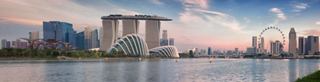 Une skyline dynamique de Singapour mettant en avant des bâtiments modernes et la grande roue emblématique au bord de l'eau | MSC Cruises