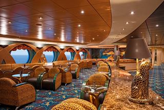 A warm and inviting sitting area in The Savannah Bar, featuring comfortable armchairs and porthole windows | MSC Cruises