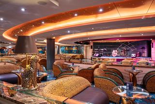 A welcoming lounge area with comfortable seating and a stage for live performances aboard the MSC Orchestra | MSC Cruises