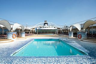 Una serena zona de piscina en el MSC Orchestra, rodeada de tumbonas y espacios públicos, invita a relajarse al sol | MSC Cruceros
