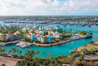 A scenic view of Nassau in the Bahamas, showcasing colourful houses by the turquoise sea and palm trees | MSC Cruises