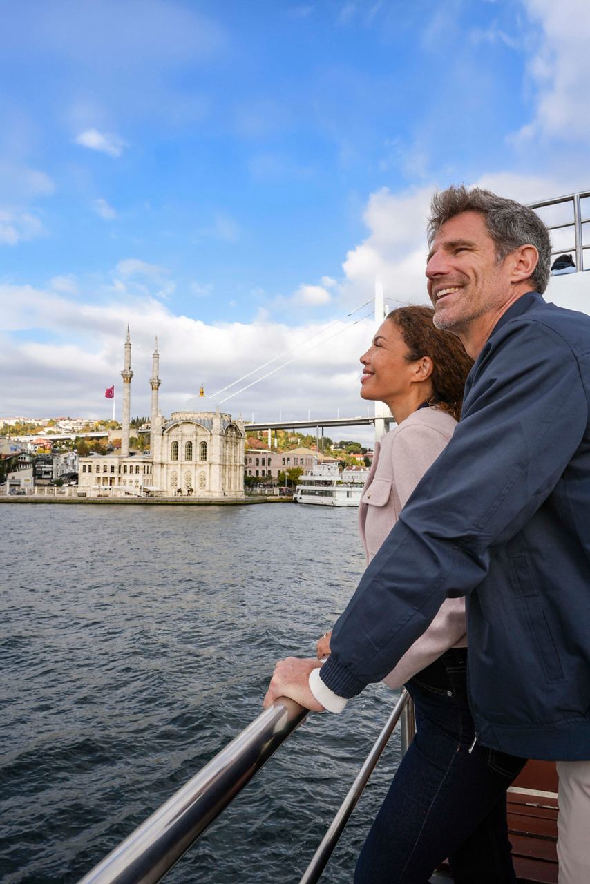 A couple enjoys a Bosphorus cruise with Ortaköy Camii in the background, embracing the beauty of Istanbul | MSC Cruises
