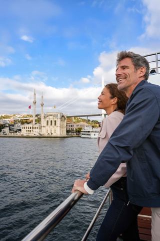 A couple enjoys a Bosphorus cruise with Ortaköy Camii in the background, embracing the beauty of Istanbul | MSC Cruises