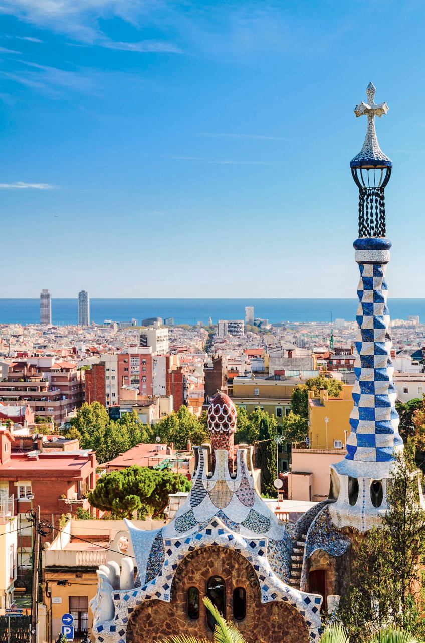 A stunning view of Parc Güell in Barcelona, featuring a decorative column and the Mediterranean Sea in the background | MSC Cruises
