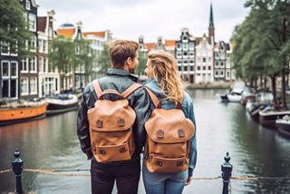 Un couple se tient ensemble près d'un canal à Amsterdam, profitant de la vue pittoresque sur les bâtiments et les environs vibrants | MSC Cruises