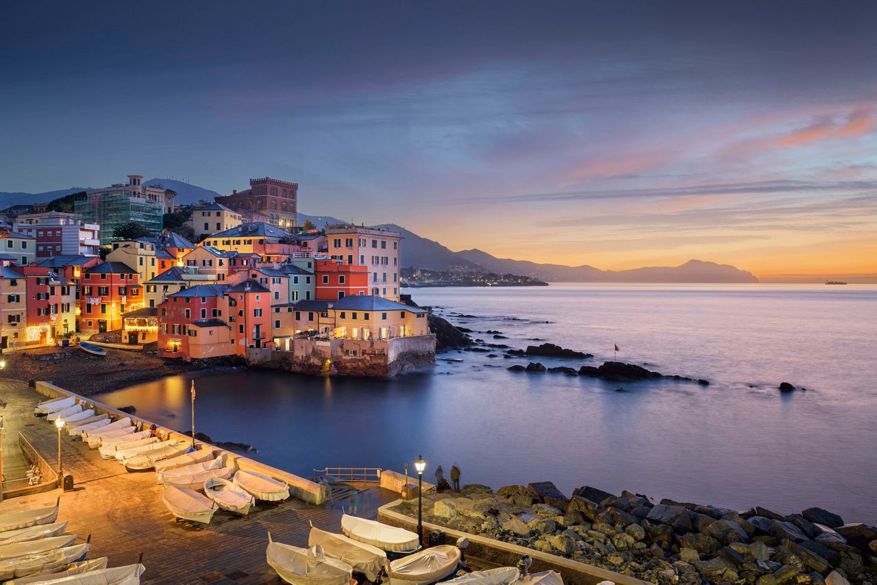 Una vista costiera affascinante di Boccadasse a Genova al crepuscolo, con edifici colorati lungo la costa | MSC Crociere