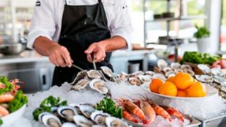 A chef prepares fresh seafood, including prawns and oysters, on a beautifully arranged ice display | MSC Cruises