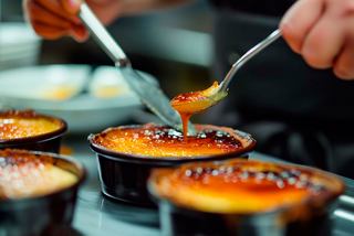 Gros plan sur une main servant de la crème catalane, un dessert sucré, dans un cadre méditerranéen | MSC Croisières