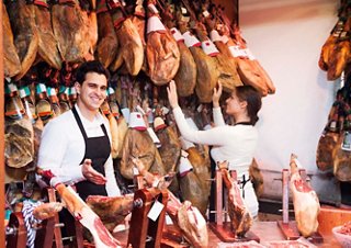 Une scène de marché animée avec deux bouchers montrant fièrement leur jamón à Barcelone, Espagne | MSC Croisières