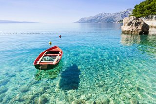 Ein kleines Boot schwimmt auf kristallklarem Wasser in einer ruhigen kroatischen Landschaft | MSC Cruises