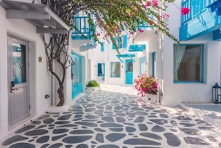 Charming whitewashed buildings and vibrant flowers create a welcoming atmosphere in a Santorini street | MSC Cruises