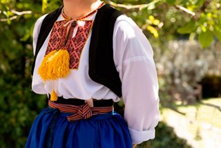 A woman in traditional Croatian dress stands proudly, showcasing her cultural heritage in the beautiful Konavle region | MSC Cruises