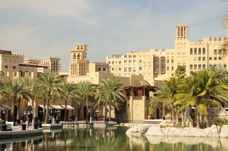 Una vista pintoresca del zoco Madinat Jumeirah con edificios, árboles y un canal bajo un cielo despejado | MSC Cruceros