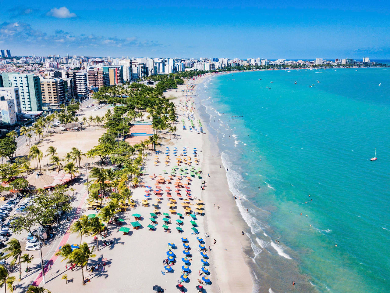 Aerial view of Praia de Pajuçara beach, featuring sandy shores, clear sea, palm trees, and nearby buildings | MSC Cruises