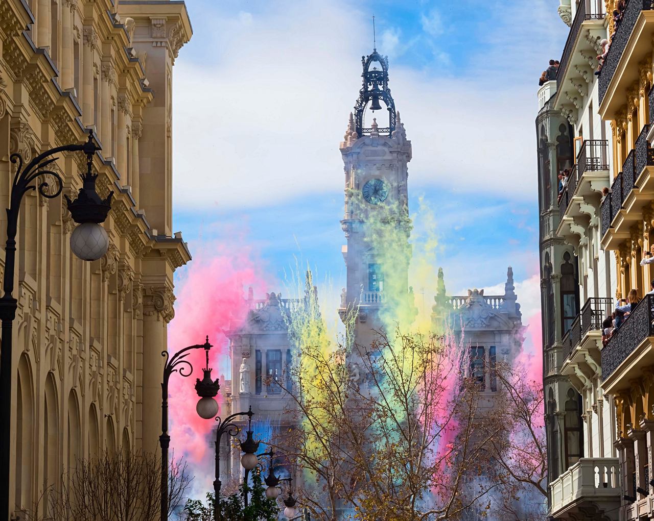 Una escena callejera vibrante durante el festival Las Fallas en Valencia, con decoraciones festivas y la icónica torre del reloj | MSC Cruises
