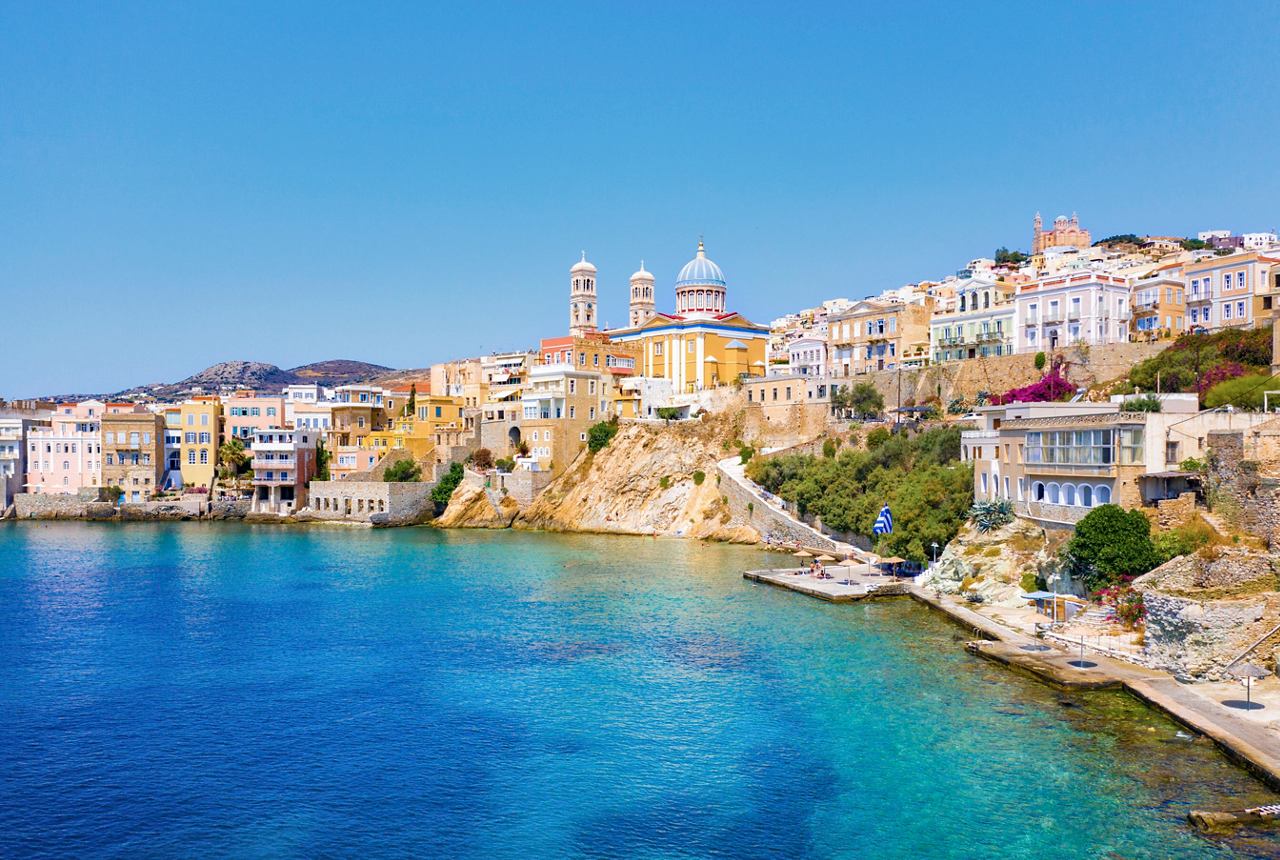 Charmanter Küstenblick auf Ermoupoli in Syros, Griechenland, mit bunten Gebäuden vor einem klaren blauen Himmel | MSC Cruises