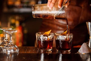 A bartender serves refreshing cocktails with ice and garnishes at a stylish bar counter | MSC Cruises
