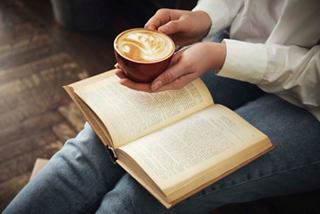 A woman enjoys a cappuccino while reading a book in a cozy setting | MSC Cruises
