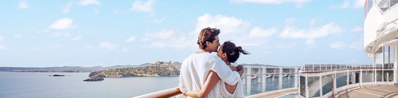 Ein Paar genießt einen romantischen Moment am Meer mit einem schönen Blick auf Ibiza im Hintergrund | MSC Cruises