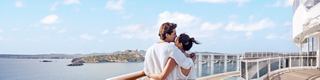 A couple enjoys a romantic moment by the sea, embracing with a beautiful view of Ibiza in the background | MSC Cruises