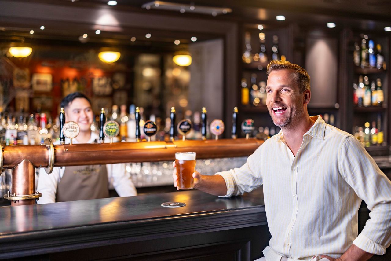A smiling crew member serves a beer at the bar, enhancing the vibrant atmosphere onboard | MSC Cruises