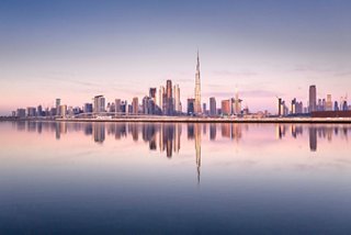 Un lever de soleil serein illuminant la skyline de Dubaï reflété dans des eaux calmes | MSC Croisières