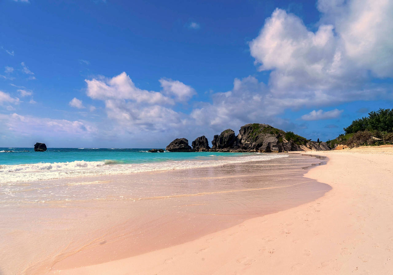 A serene view of Horseshoe Bay Beach with soft sand, gentle waves, and a bright blue sky | MSC Cruises