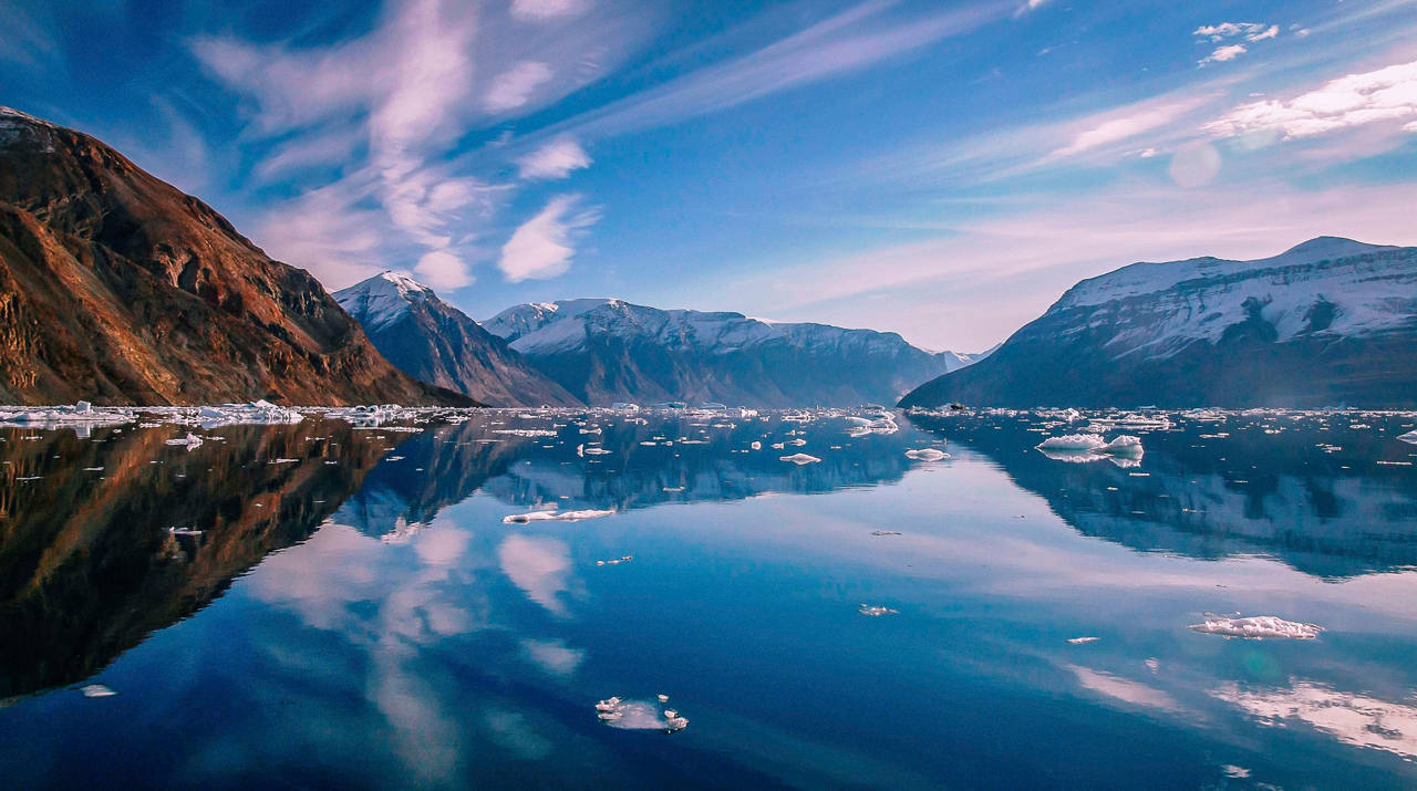 A tranquil reflection of mountains and sky over Kejser Franz Joseph Fjord in Greenland | MSC Cruises