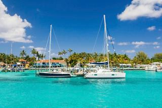 Sailboats anchored in turquoise waters, surrounded by lush palm trees and a clear blue sky | MSC Cruises