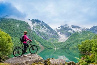 A cyclist stands on a rock, overlooking stunning Norwegian fjords and mountains in Northern Europe | MSC Cruises