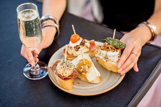 Une personne déguste de délicieuses tapas avec un verre de boisson pétillante dans un cadre chaleureux | MSC Croisières