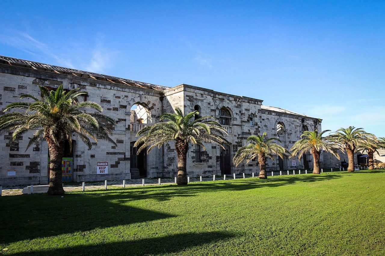 The Victualling Warehouse in Bermuda surrounded by lush gardens and palm trees under a clear blue sky | MSC Cruises