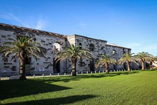 The Victualling Warehouse in Bermuda surrounded by lush gardens and palm trees under a clear blue sky | MSC Cruises
