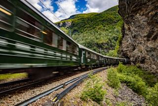 A scenic train travelling through lush green hills in Flaam, Norway, showcasing the beauty of Northern Europe | MSC Cruises