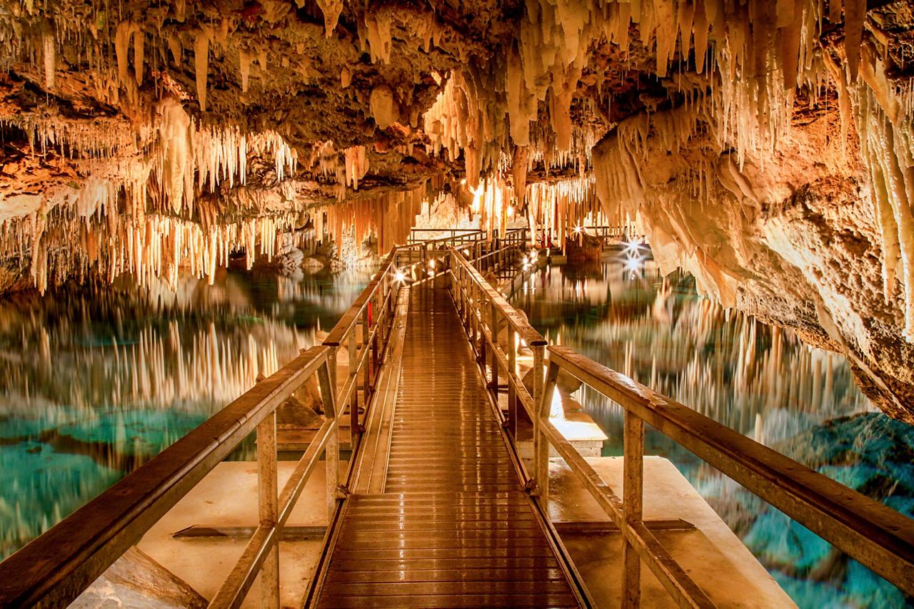 A wooden walkway leads into the stunning natural formations of the Crystal Caves in Bermuda | MSC Cruises