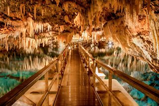 A wooden walkway leads into the stunning natural formations of the Crystal Caves in Bermuda | MSC Cruises