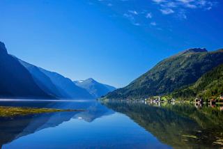 Serene fjord landscape surrounded by majestic mountains under a clear blue sky | MSC Cruises