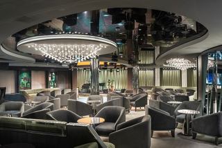 A stylish bar area featuring comfortable seating, a stage, and a piano for entertainment | MSC Cruises