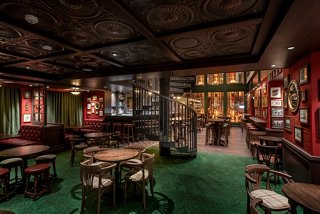 A vibrant pub setting featuring a winding staircase, tables, and a cozy sitting area for guests to enjoy | MSC Cruises