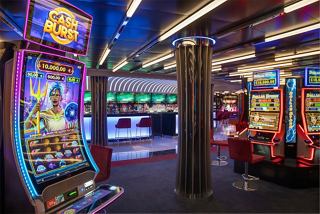 A vibrant casino area featuring slot machines and a bar counter, inviting guests to enjoy entertainment and relaxation | MSC Cruises