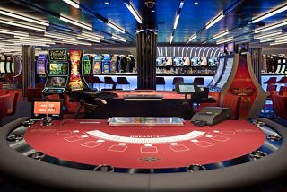 A vibrant casino area featuring a red gaming table, slot machines, and a stylish bar counter | MSC Cruises