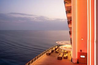 A serene view from the balcony overlooking the sea and sky, featuring palm tree lights and a cosy sitting area | MSC Cruises