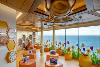 A vibrant family entertainment area with colourful seating and a large glass wall offering sea views | MSC Cruises